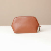 Brown leather pouch on a white surface with a beige background