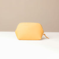 Yellow pouch on a white surface with a beige background