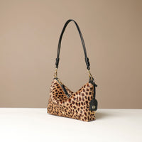 Leopard print crossbody Danilos bag with black handle on a beige background