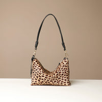 Leopard print crossbody Danilos bag with black strap on a beige background
