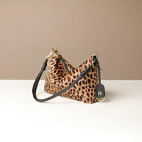 Leopard print crossbody Danilos bag with black strap on a beige background