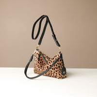 Leopard print crossbody Danilos bag on hair on leather with black strap on a beige background