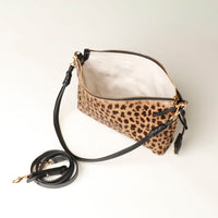 Opened Leopard print crossbody Danilos bag with a black strap on a light background