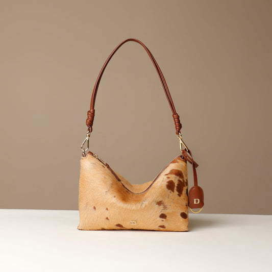 Brown leather crossbody Danilos bag with cowhide pattern on a beige background