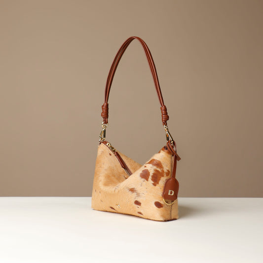 Cowhide leather crossbody Danilos bag with brown handle on a beige background