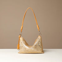 Gold and yellow crossbody Danilos bag with a textured surface on a beige background