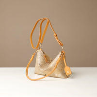 Gold and yellow crossbody Danilos bag with a strap on a white surface and beige background