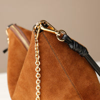 Brown suede Danilos handbag with gold chain and black handle on a neutral background