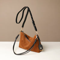 Brown Danilos suede handbag with black strap on a beige background