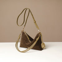 green suede Danilos handbag with a strap on a white surface and beige background