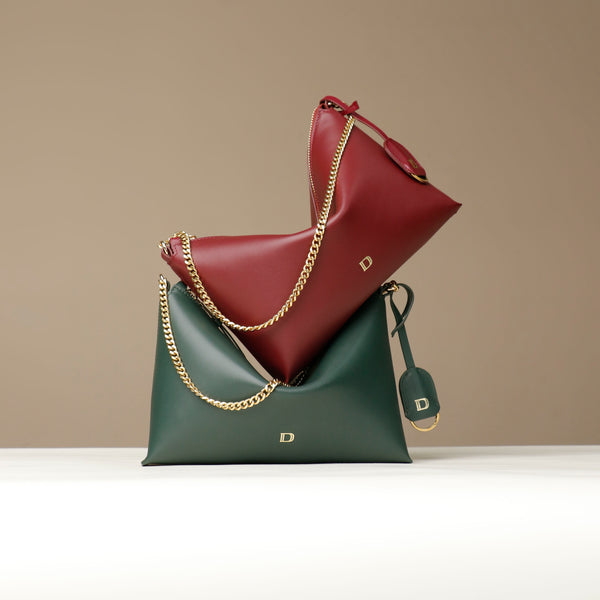 Two leather Danilos handbags, one green and one red, with gold chains on a beige background.