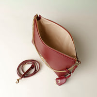 Red opened Danilos handbag with gold chain strap on a light background
