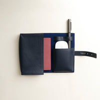 Front view of a open marine blue Danilos Pebble executive accessory holder linea on a beige background