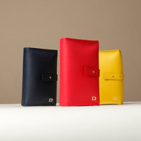 Front view of three Danilos Pebble executive accessory holder linea in red, marine blue and yellow colors on a beige background