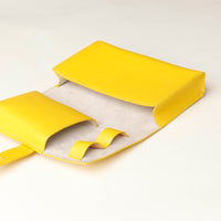 close up view of a open empty yellow Danilos Pebble executive accessory holder linea on a beige background