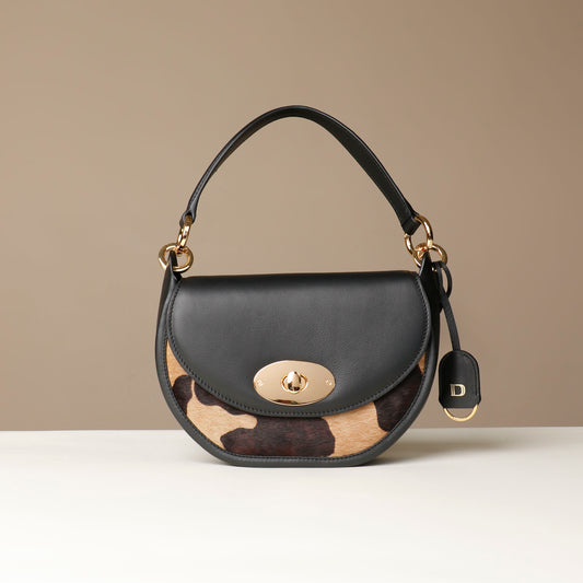 Danilos round hair on leather Handbag with cowhide pattern on a beige background