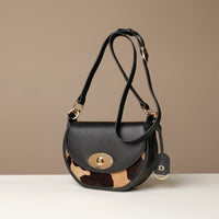 Black Danilos round hair on leather  handbag with a cowhide pattern on a beige background