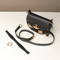 Black Danilos round hair on leather  handbag with gold accents on a white surface