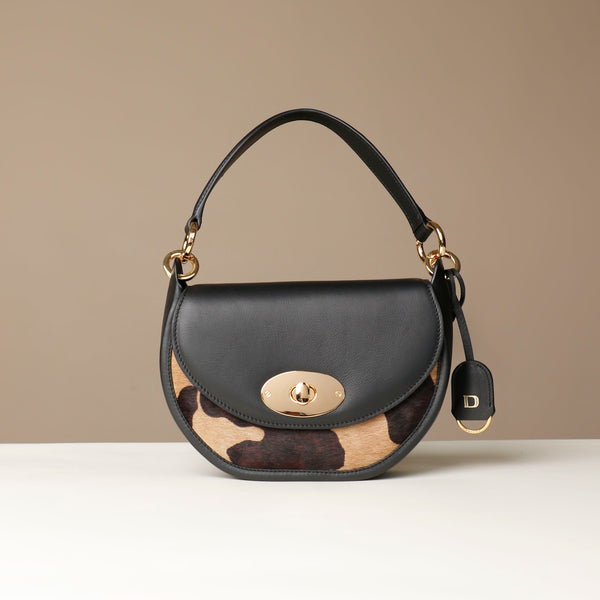 Danilos round hair on leather Handbag with cowhide pattern on a beige background