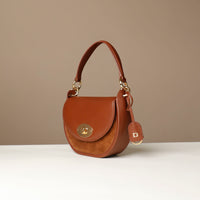 Brown Danilos handbag with gold accents on a beige background
