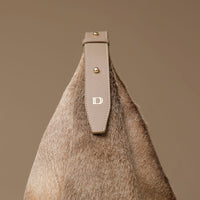 close up handbag with a leather strap and hair on leather on a brown background with a visible Danilos logo