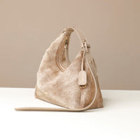 Beige hair on leather Danilos handbag with a strap on a white surface and beige background
