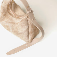 Beige hair on Danilos leather handbag with a textured surface and leather strap on a light background