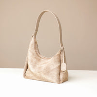 Beige hair on Danilos leather handbag on a white surface with a beige background