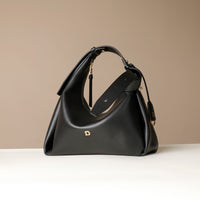 Black leather handbag with the Danilos logo on a beige background