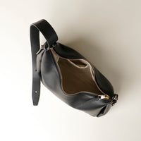 upper view Black leather Danilos handbag with a gold zipper on a light beige background