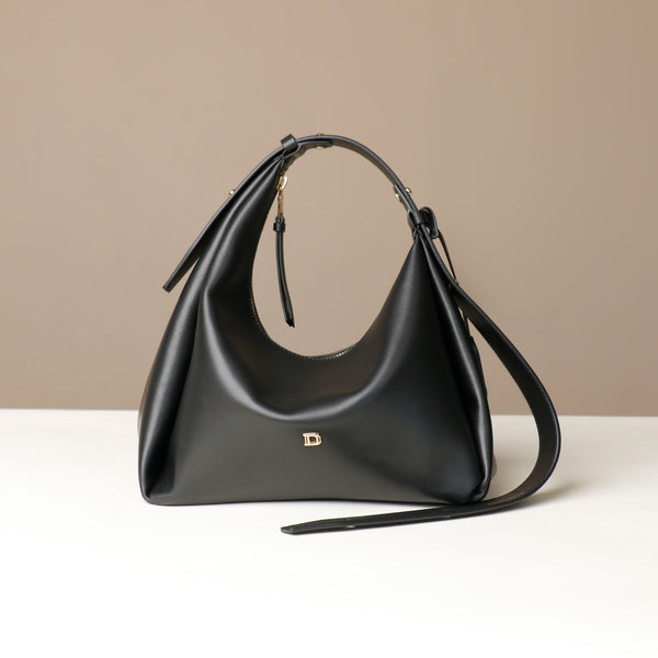 Black leather Danilos handbag with a strap on a beige background