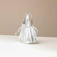 Side view of a Danilos Handbag mini papillon junior in metallic silver color leather over a beige background