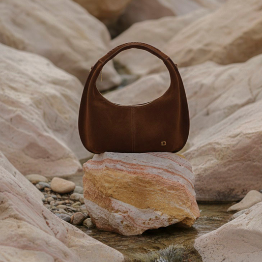 Brown suede leather danilos handbag on a rock with a natural stone background