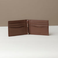 Front view of an open Danilos pebble marine brown leather money clip Steven, with 6 card slots, in a beige background