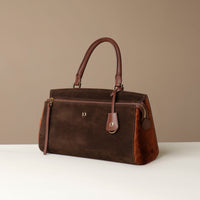 Brown suede leather Danilos handbag on a white surface with a beige background and hair on leather on the side