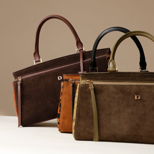 Three leather Danilos handbags in brown, light brown, and green on a neutral background