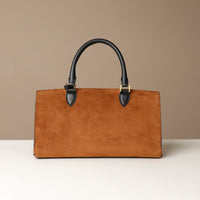 Brown suede Danilos handbag with black handles on a beige background