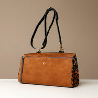 Brown suede Danilos handbag with leopard black and gold accents on a beige background
