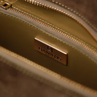Close-up of a gold handbag with 'DANILOS' logo on a blurred background