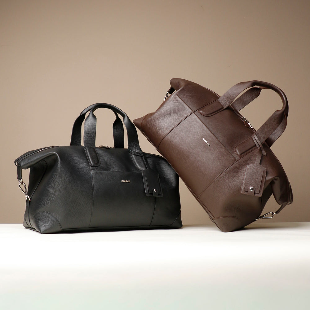 Black and brown leather travel bags on a beige background