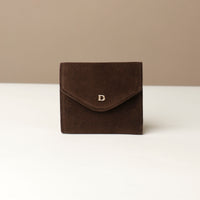 Brown suede wallet with a visible brand logo on a white surface with a beige background
