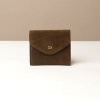 Green suede wallet with a brand logo on a beige background