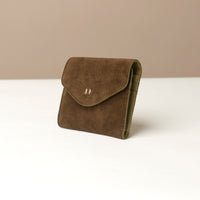 Brown suede wallet on a white surface with a beige background