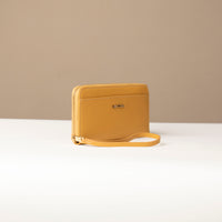 side view of a Yellow Danilos wallet Carlota with a visible handle drop and a gold zipper in a beige background