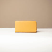 back view of a Yellow Danilos wallet Carlota in a beige background