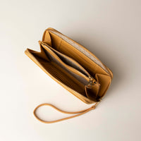 upper view of a open Yellow Danilos wallet Carlota with a visible handle drop and a gold zipper in a beige background
