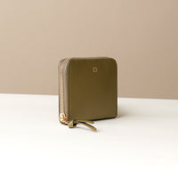 side view of a green zurich sr danilos leather wallet with gold zipper over a beige background