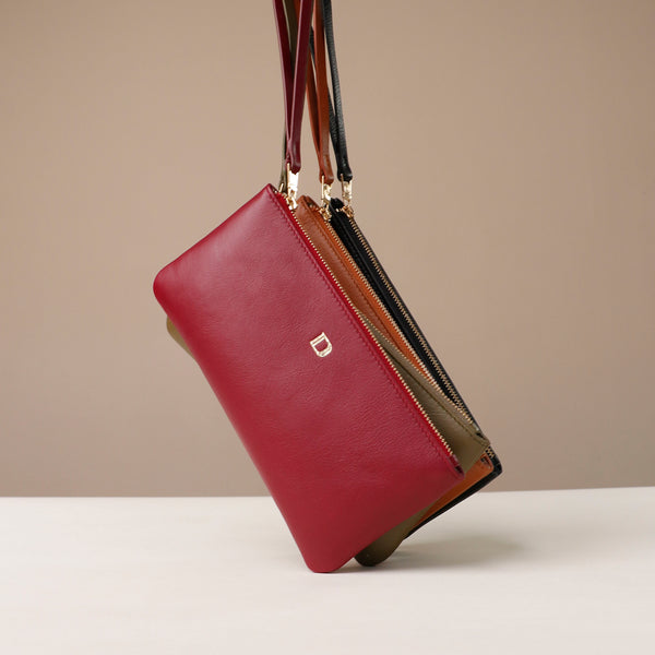 red danilos leather wristlet pouch julia jr in red, green,orange and black colors over a beige background